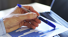 Close-up of hand holding a pen on a piece of paper with a graph